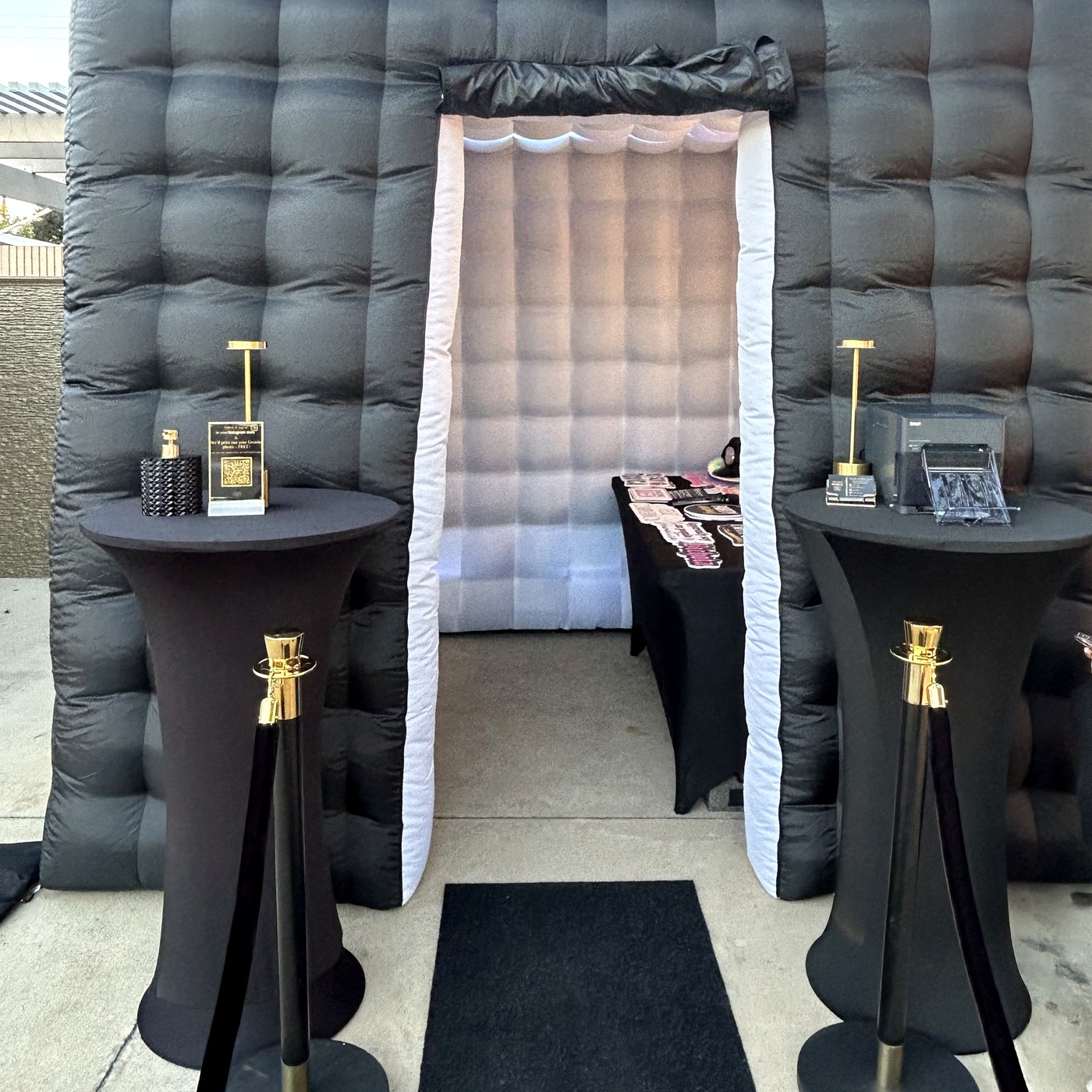 Black inflatable photo booth setup with stanchions and premium tables