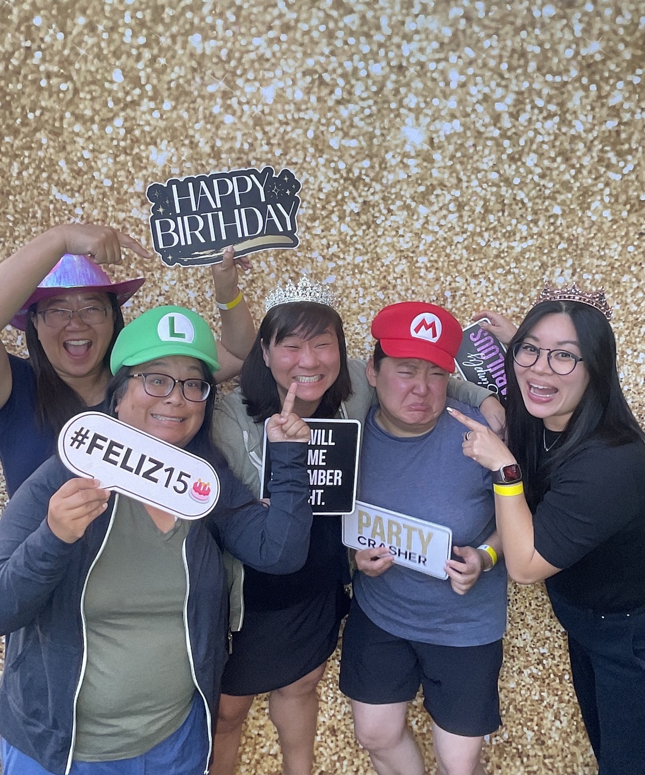 Jenn’s 50th Birthday guests posing with party props in front of a gold backdrop by Studio RDRGZ LA